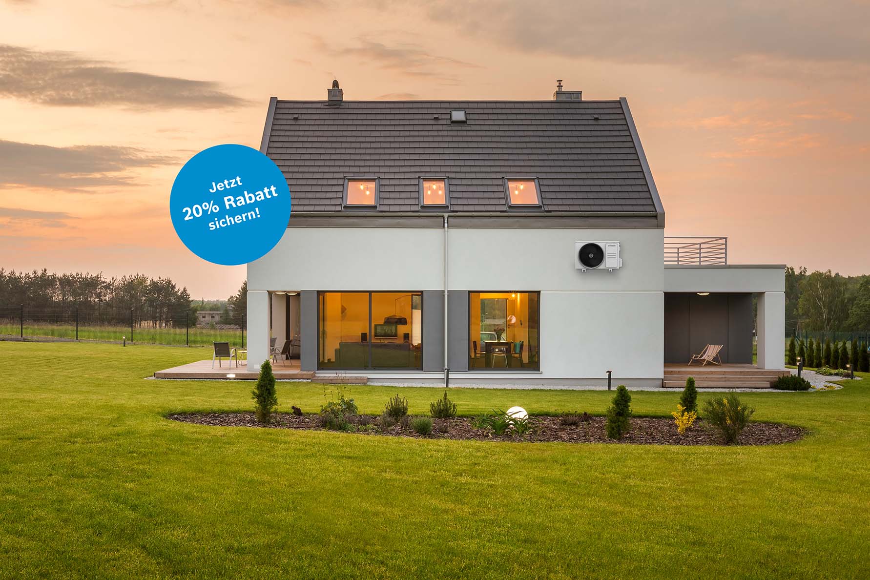 Ein modernes wei&szlig;es Haus mit gro&szlig;en Fenstern steht bei Sonnenuntergang auf einem gepflegten Rasen. In einem blauen Kreis auf dem Bild steht: 